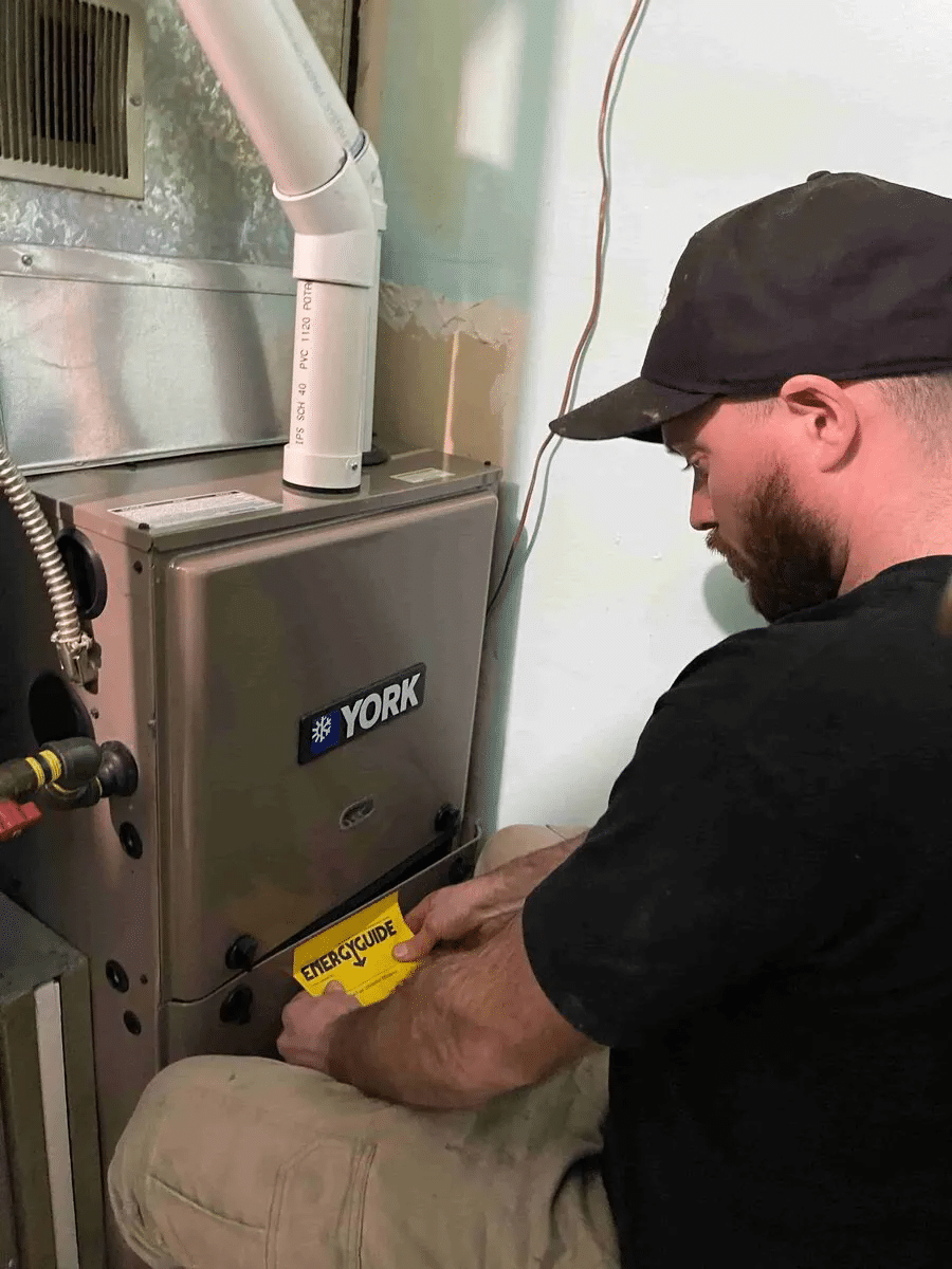 Staff members repairing a York brand air conditioning unit in a well-lit service area. Tools and equipment are visible.