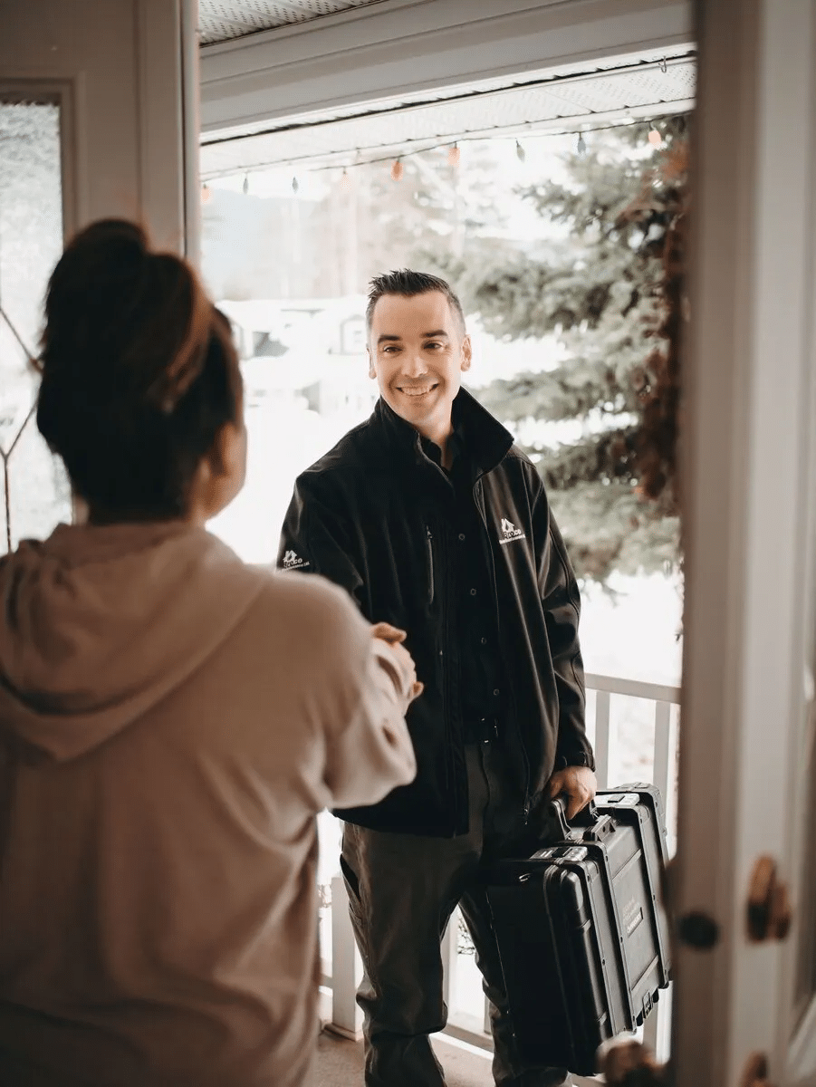 A man smiling at a woman while holding a briefcase during a staff meeting with a client.