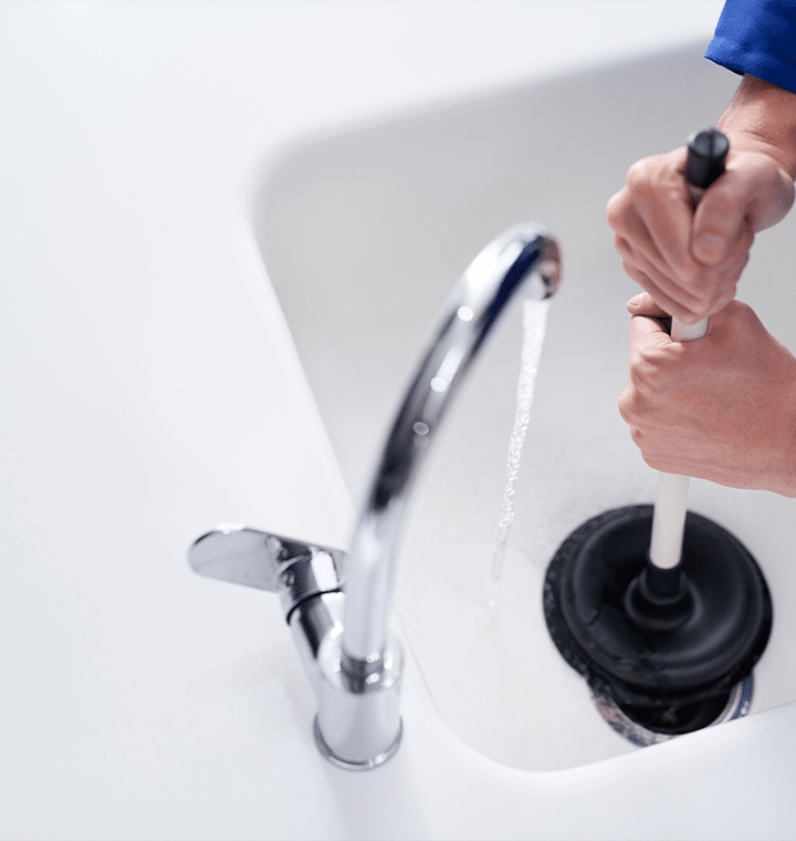Man using a pump to drain water from a faucet, focused on the task with a determined expression.
