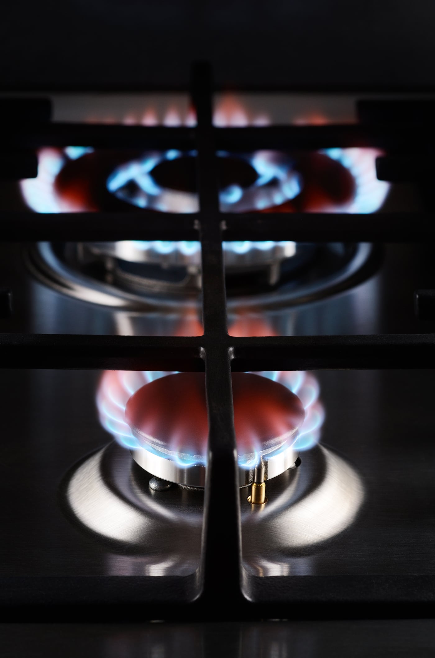A gas stove with two blue flames lit, indicating it is in use for cooking.