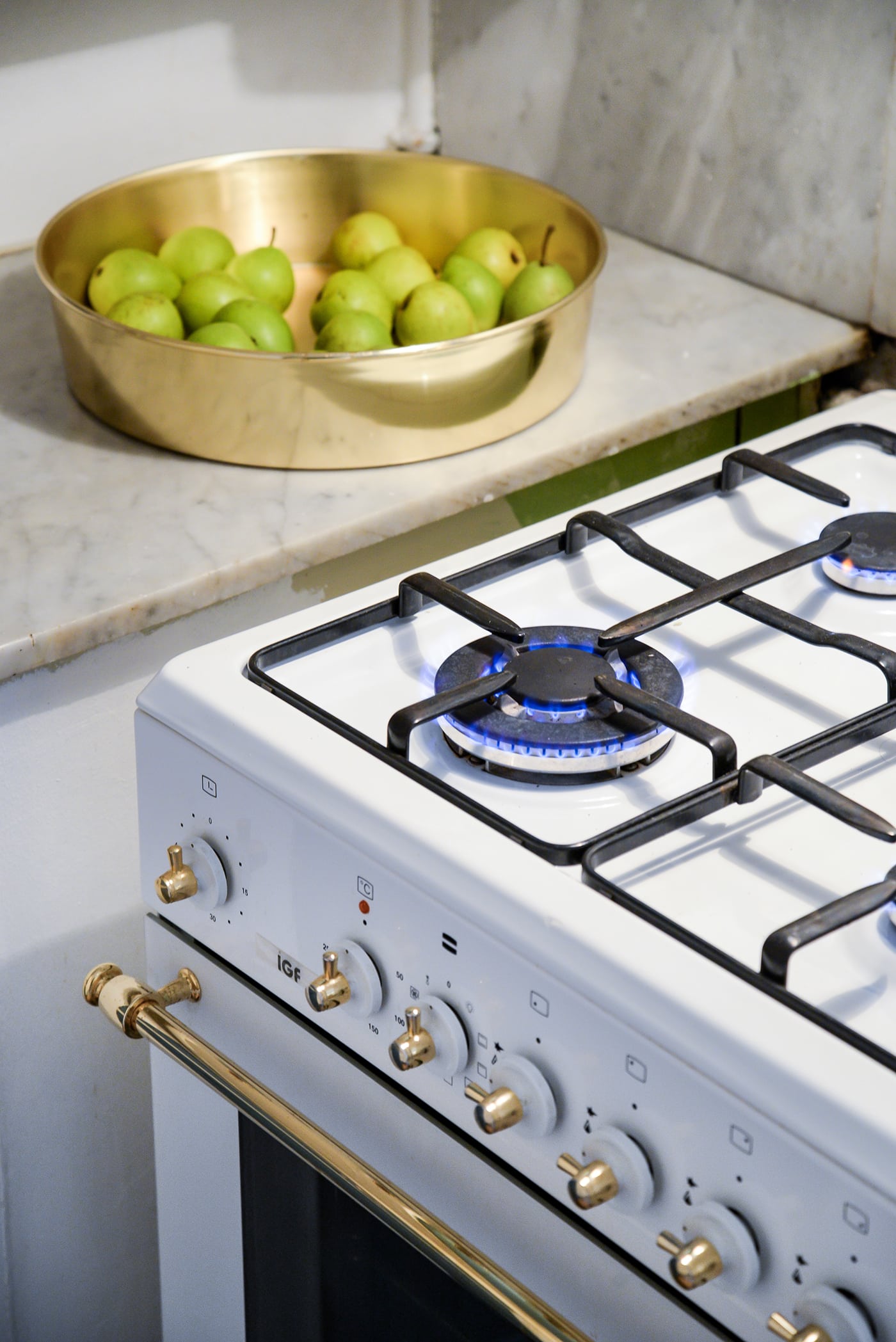 A vertical high angle shot of a burning stove and a bowl with pears in the kitchen